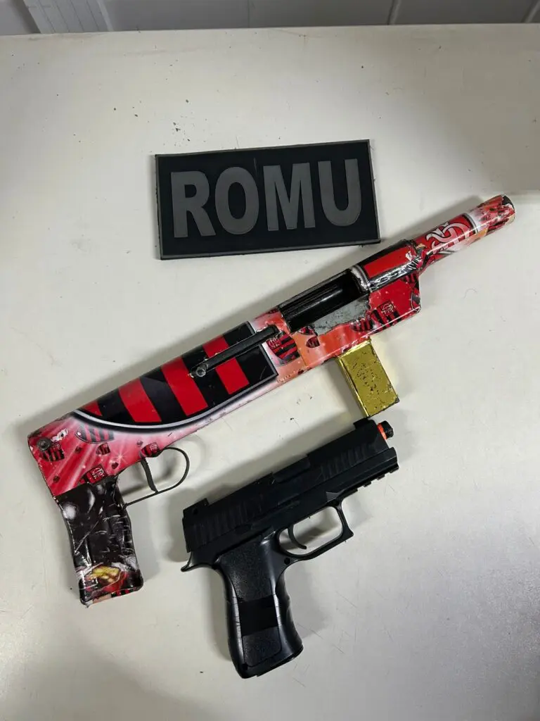 Sobre uma mesa, uma arma de fabricação caseira e simulacro de pistola foram apreendidos durante a ocorrência.