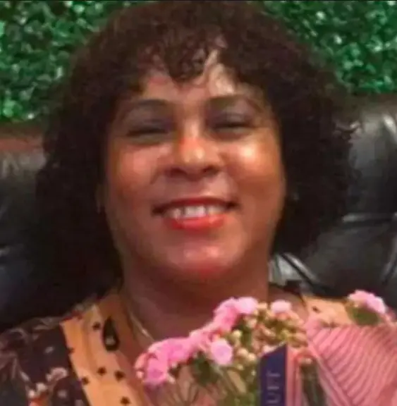 Imagem de uma mulher (Ivanilda de Araújo dos Reis, de 51 anos), segurando um vaso de flores. 