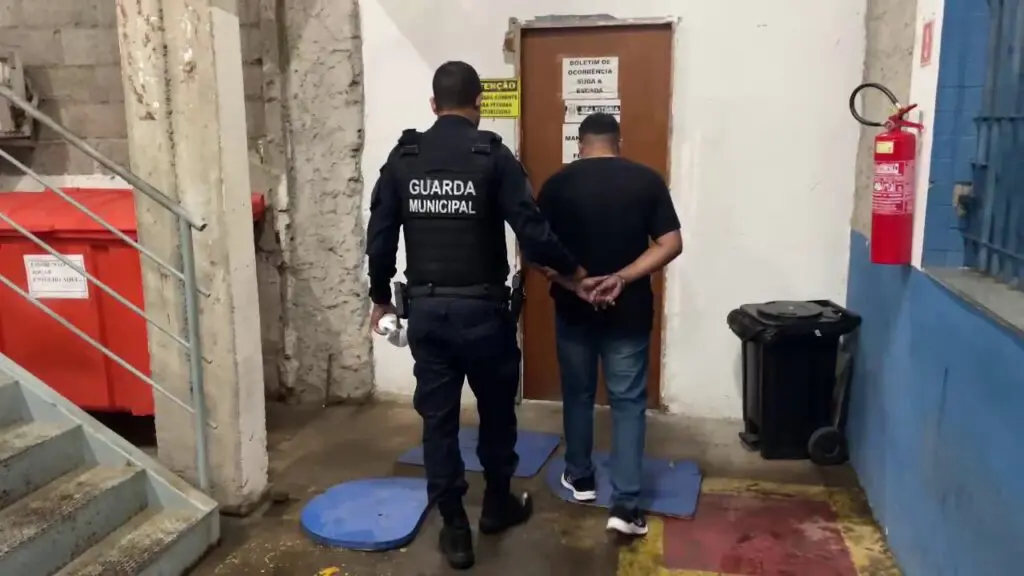 Imagem de um agente da Guarda de Vitória, levando um sujeito algemado para a delegacia da região.