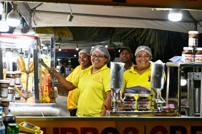 Um quiosque de churros com 3 mulheres e um homem funcionários do local sorrindo enquanto posam para uma foto.