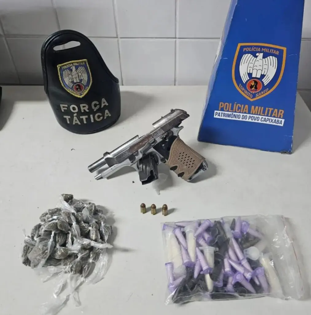 Sobre uma mesa uma pistola calibre .380, 60 buchas de maconha e 82 pinos de cocaína.