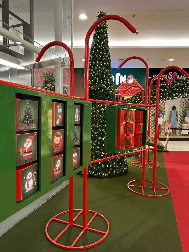 Imagem de um shopping com um local decorado com objetos natalinos.