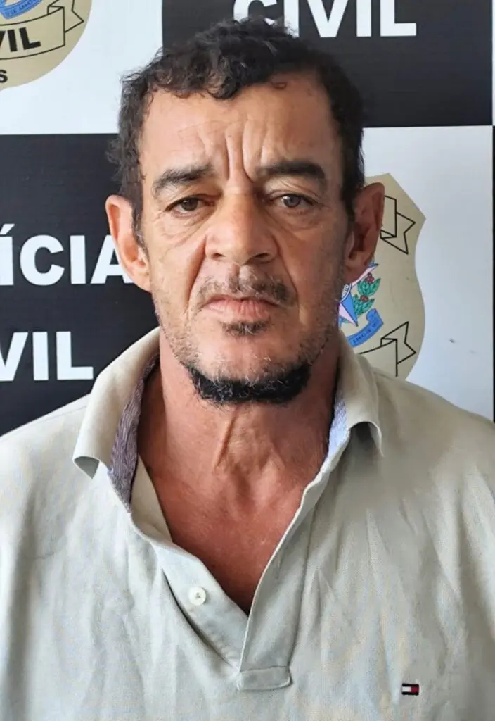 Imagem de um homem (Uadson Gomes Santos, de 58 anos) em frente a uma parede com imagens de divulgação da Polícia Civil.