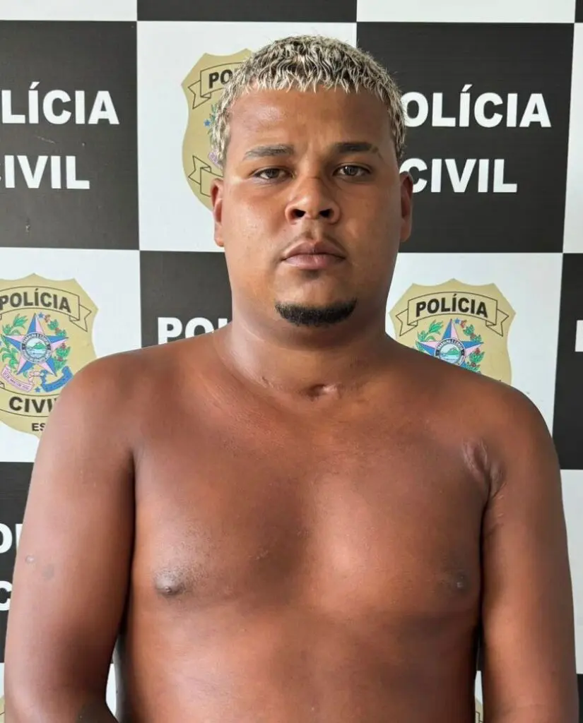 Imagem de um homem (Marlon Nascimento da Conceição, vulgo “Marlin", 23 anos) em frente a uma parede com imagens de divulgação da Polícia Civil.