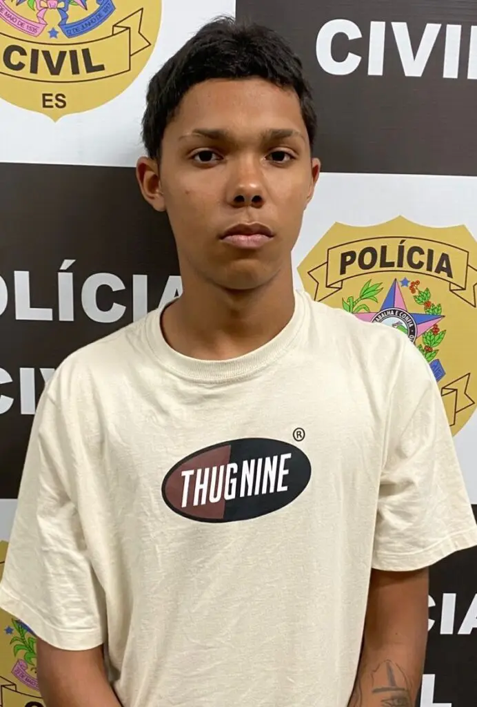 Imagem de um homem (Talysson Filipe Lima da Silva, vulgo “Talyssinho”, 20 anos) em frente a uma parede com imagens de divulgação da Polícia Civil.
