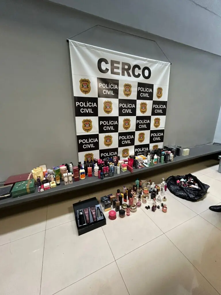Imagem de uma sala de uma delegacia com centenas de produtos de beleza expostos no chão e na bancada.