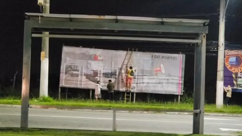 Outdoor com cobrança ao prefeito Weverson Meireles sendo retirado em apenas um dia após instalação na Avenida Brasília, em Planície da Serra.
