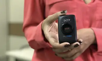 Uma mulher segurando um objeto com um botão do pânico.