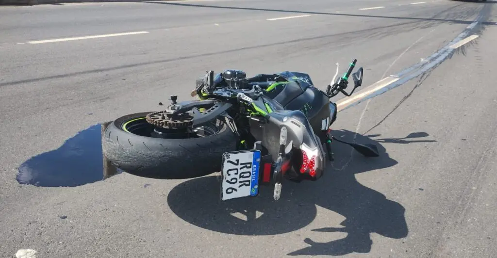 Uma moto caída em uma pista sem a roda dianteira.