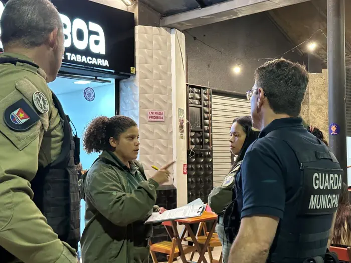 Imagem de uma fiscal ao lado de dois policiais e um agente da Guarda de Vitória durante uma vistoria em um bar.