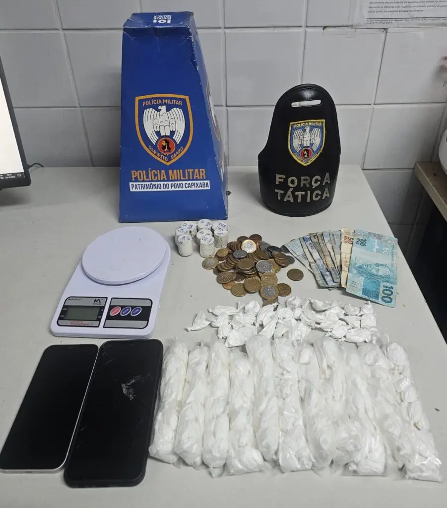 Imagem de dois celulares, vários sacos com cocaína moedas, materiais apreendidos durante a ocorrência.