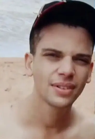 Imagem de um jovem (Thiago Gonçalves Stoffel, de 26 anos), usando um boné em uma praia.