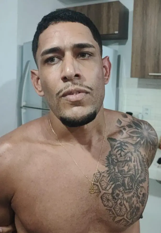 Imagem de um homem sem camisa com os braços para trás após ser preso.