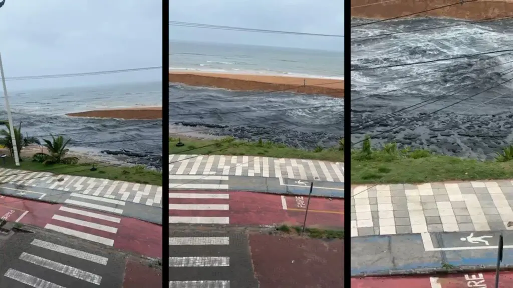 Fluxo de água escura da Lagoa de Carapebus, na Serra, desaguando na praia após romper barreira de areia.