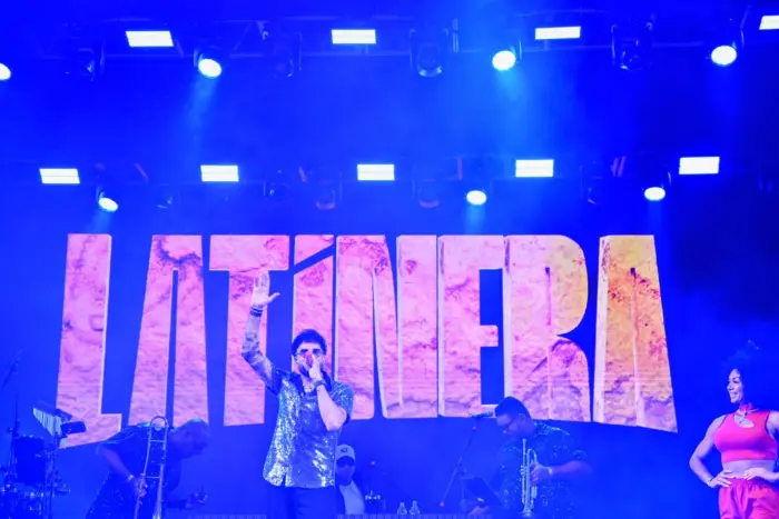 Imagem de um palco com o cantor Latino se apresentando.