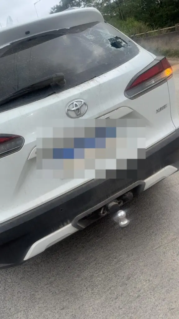 Um carro estacionado em uma avenida com marcas de tiros.