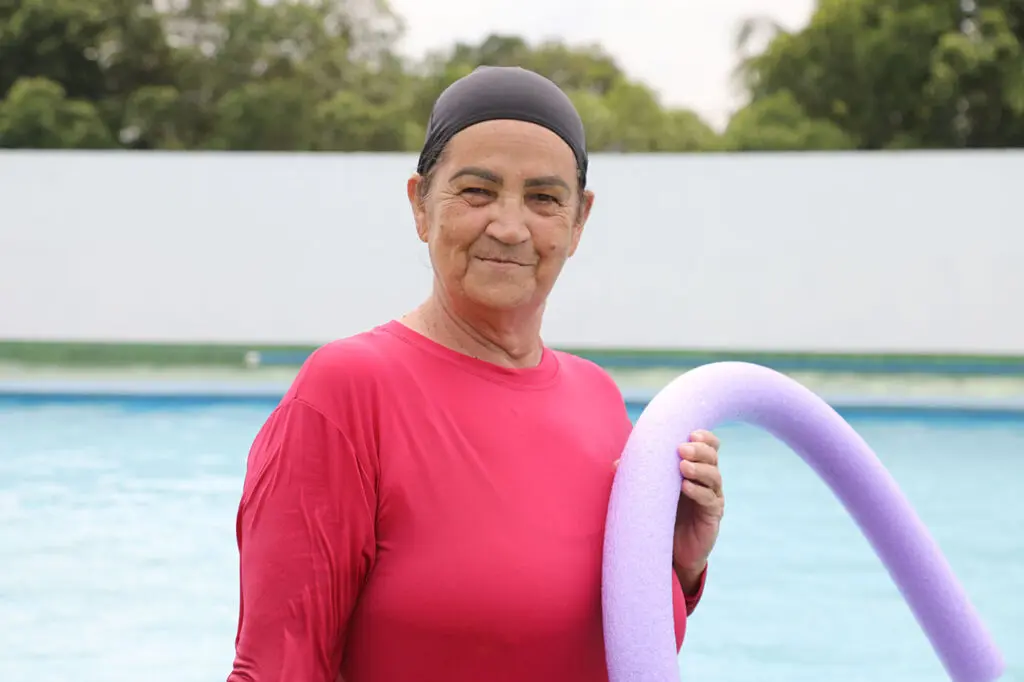 Imagem de uma idosa (Alcina Passos, de 67 anos) próximo à borda de uma piscina.