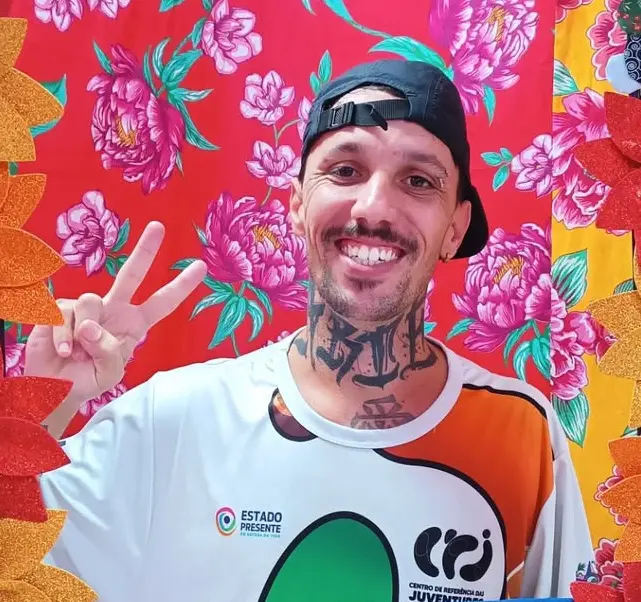 Imagem de um homem sorrindo, fazendo sinal de vitória.