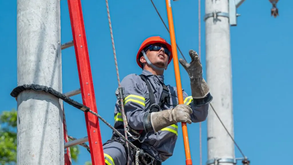 Trabalhador em poste com equipamentos de segurança em matéria sobre inscrições da Escola de Eletricistas da EDP em Serra