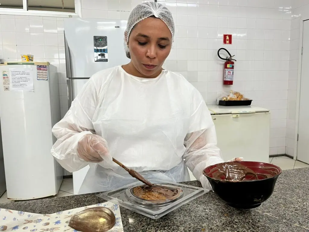 Imagem de uma mulher fazendo um ovo de Páscoa durante uma aula.