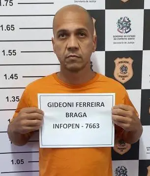 Um homem segurando uma folha de sulfite com seu nome, Gideone Ferreira Braga, de 39 anos, após ser preso pela Polícia Civil.