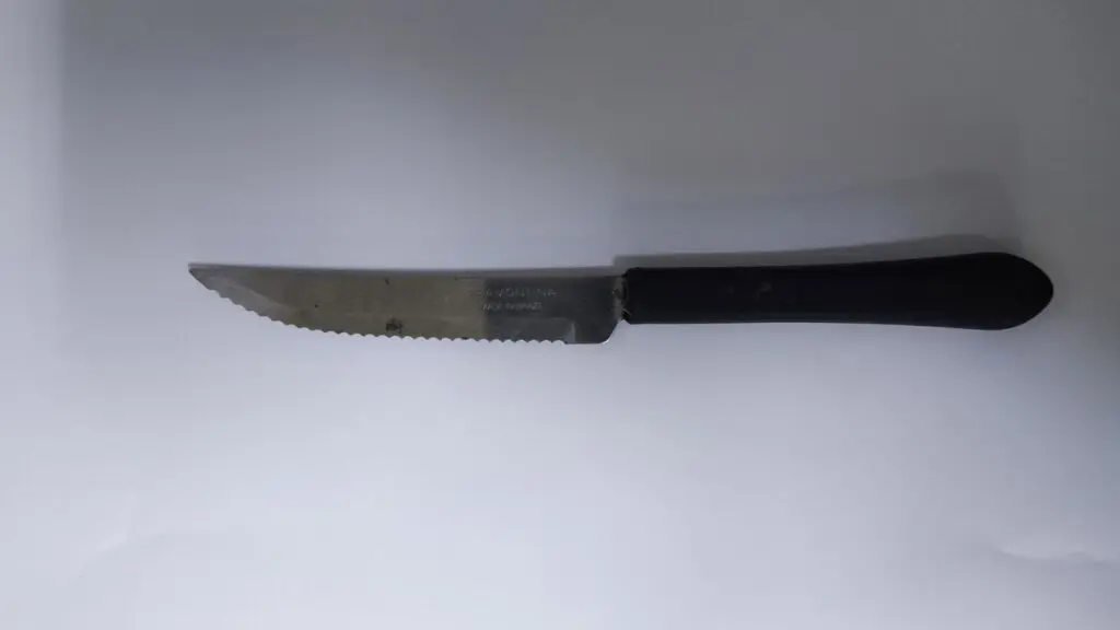 Imagem de uma faca serrilhada sobre uma mesa, apreendida durante a ocorrência de tentativa de assalto.