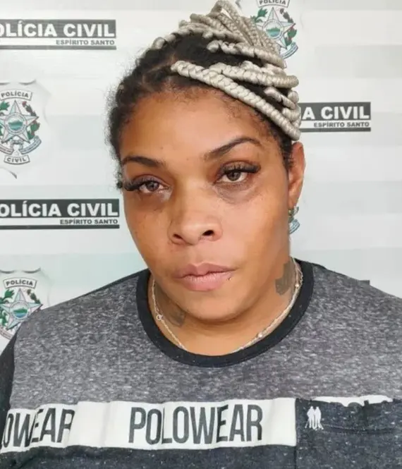 Imagem de uma mulher em frente a uma parede de identificação da Polícia Civil, após ser presa por furto.