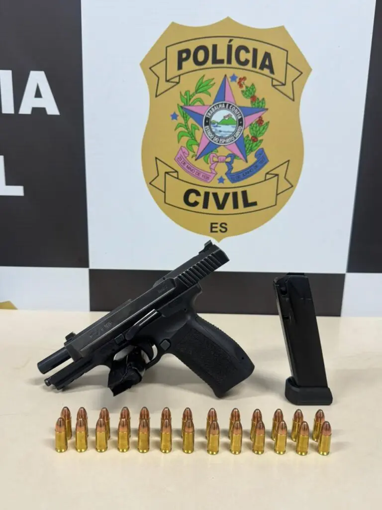 Sobre uma mesa, uma pistola, dois carregadores e 26 munições enfileiradas.