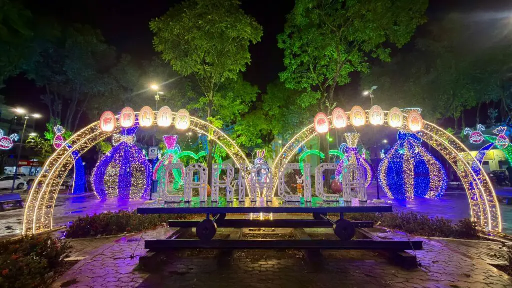 Imagem de uma praça decorada com luzes, para comemorar a Páscoa.