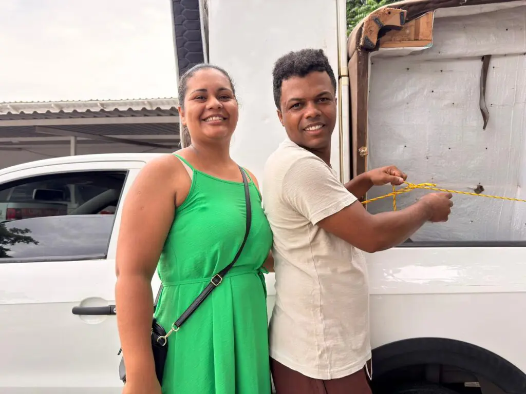 Imagem de um casal ao lado de um carro, onde está sendo colocado um sofá usado.