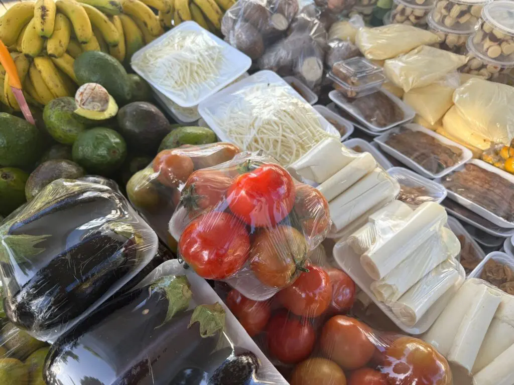 Imagem de uma banca de uma feira com diversas frutas e verduras frescas.