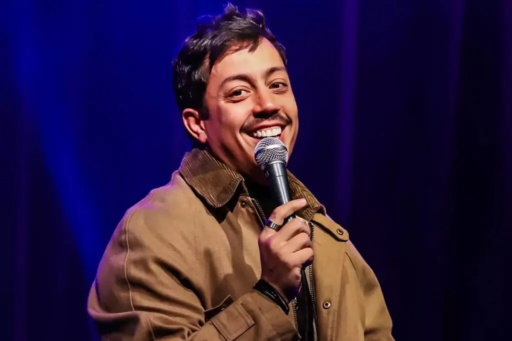 Humorista Renato Albani, sorrindo, segurando um microfone.