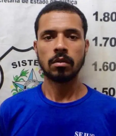 Imagem de um homem em frente a uma parede com marcações de altura.
