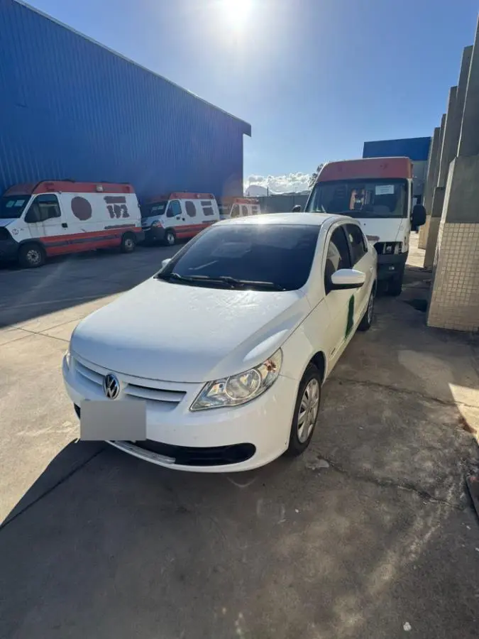 Um veículo (Volkswagen Voyage) estacionado em um pátio junto com outras ambulâncias danificadas.