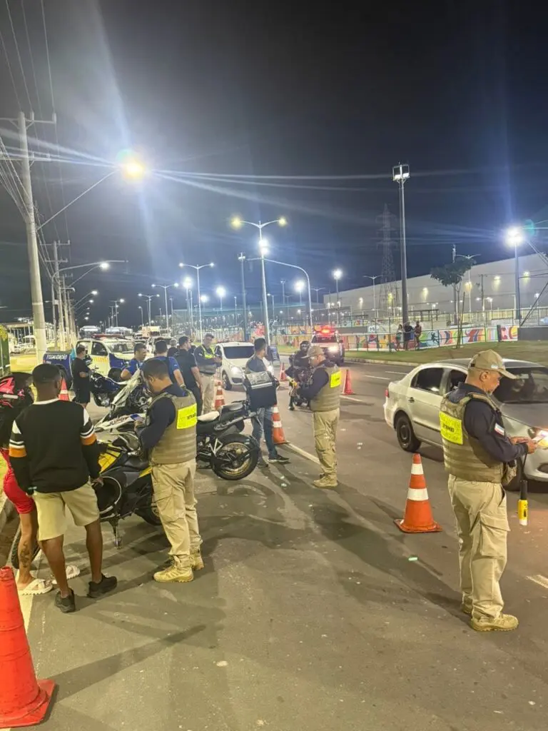 Equipes do Batalhão de Trânsito realizando a fiscalização durante a blitz em uma avenida, com diversos motoqueiros sendo abordados.