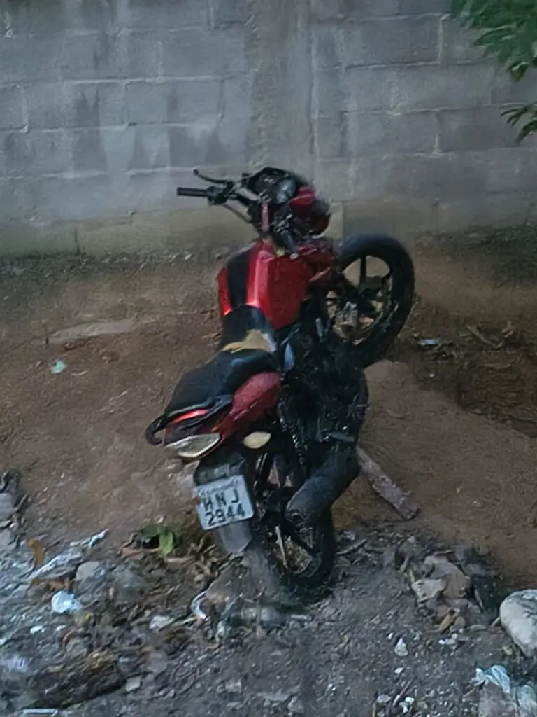 Uma motocicleta vermelha parada em um terreno.