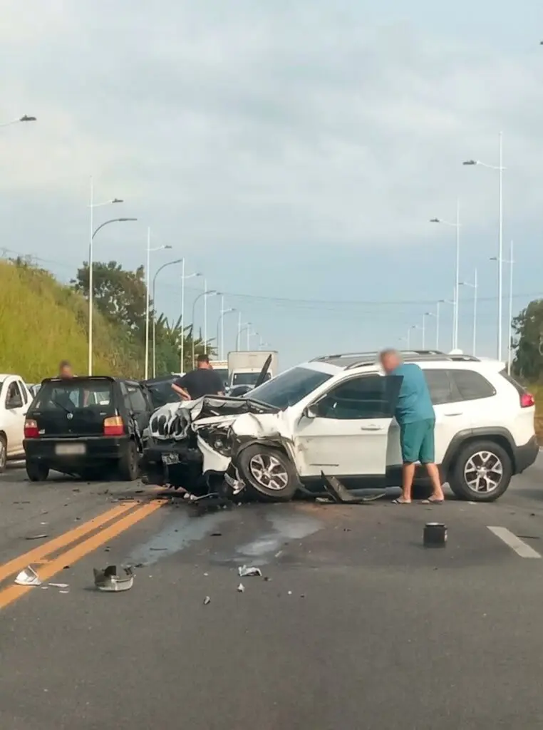 Foto de uma avenida com dois veículos, com avarias na parte frontal após uma batida. 