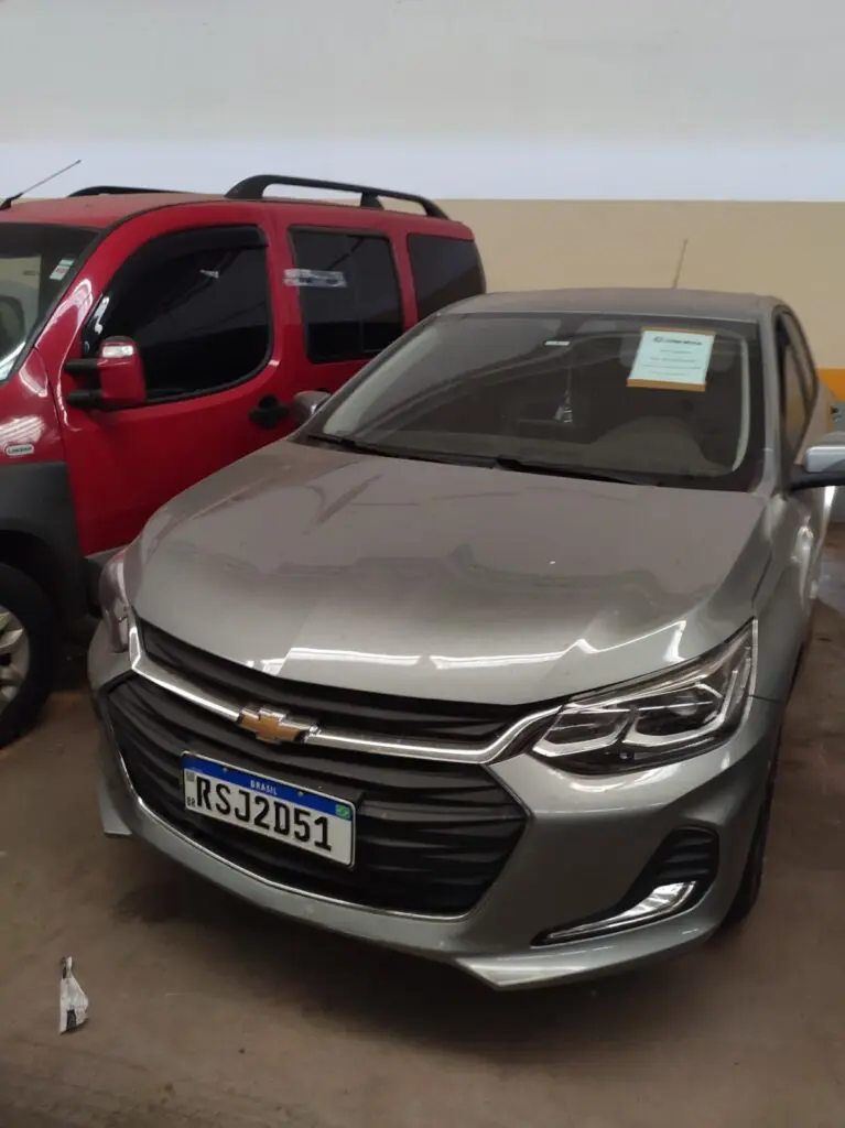 Imagem de um automóvel. Chevrolet Onix, estacionado em um pátio.