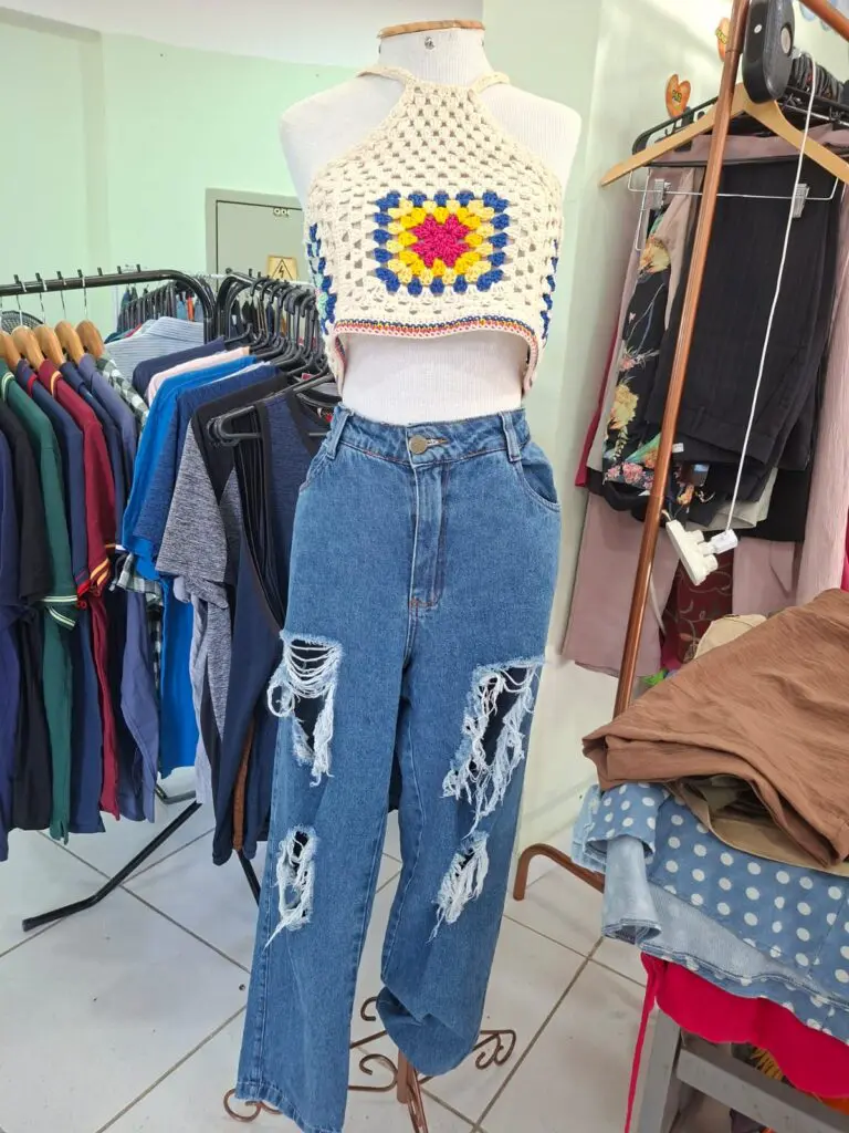Imagem de uma sala com várias araras de roupas, expostas em um brechó.