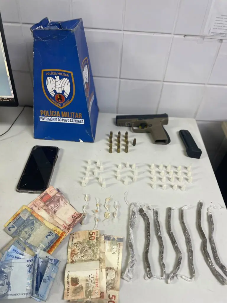 Sobre uma mesa uma pistola calibre 9mm, 13 munições, 37 pinos de cocaína, 12 pedras de crack, 7 buchas de maconha e R$ 228,00 em espécie.