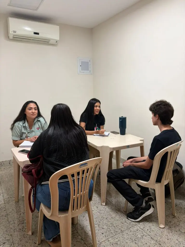 Foto de duas mulheres atendendo um jovem e uma moça no corredor de um shopping.