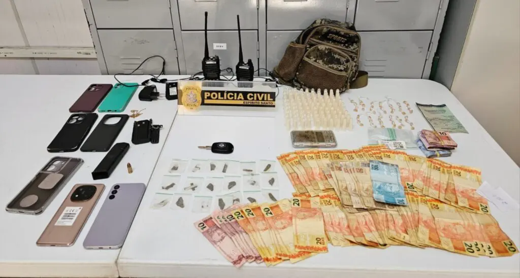 Sobre a mesa, estavam 52 pedras de crack, 18 buchas de haxixe, 90 pinos de cocaína, R$ 2.326,00 em espécie e uma munição calibre 9 milímetros, todos materiais apreendidos pela Polícia Civil na casa de um traficante.
