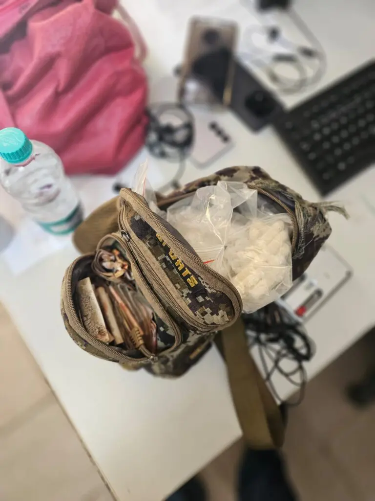 Imagem de uma mochila sobre uma mesa, aberta, com sacos contendo drogas e dinheiro em seu interior.