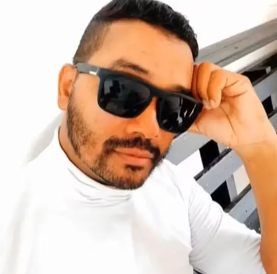 Imagem de um homem de óculos escuros posando para uma foto.