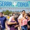 Prefeito Sérgio Vidigal abraçando uma senhora em frente a placa de divulgação do Serra mais Cidadã