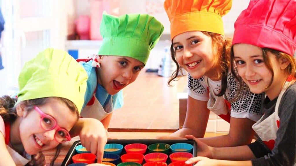 Foto de crianças com tocas de confeiteiros sorrindo e alegres
