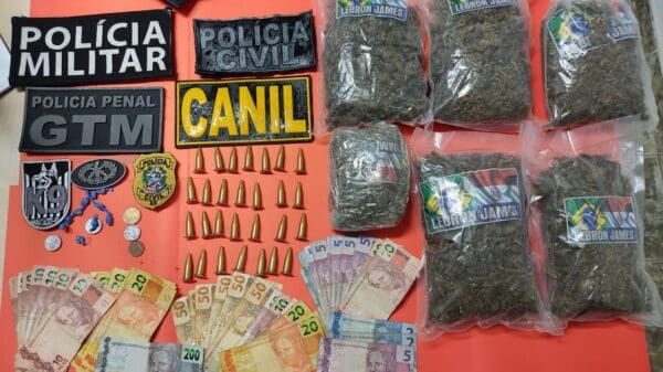 Dinheiro, sacos de maconha, pinos de cocaína sobre a uma mesa vermelha da Policia Militar
