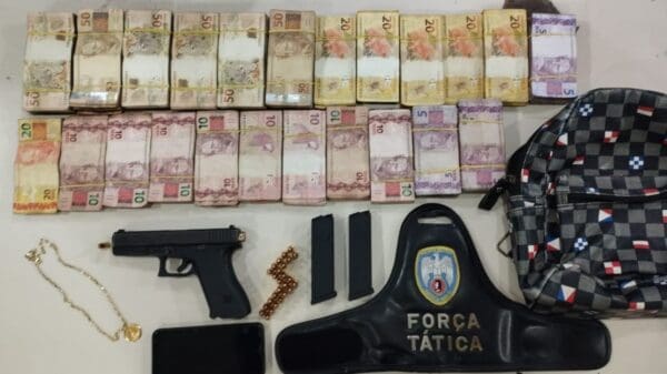 Sobre a mesa da Policia Militar oitenta mil e dez reais, uma pistola 9 milímetro, um celular, dois carregadores de pistola, uma mochila e uma braçadeira da policia militar