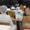 Agentes de saúde e paciente sentados em área reservada para atendimento de vacinação no Shopping Montserrat