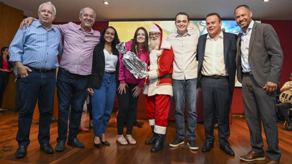 Prefeito de Vitória abraçado com servidores e homem vestido de Papai Noel em entrega de presentes